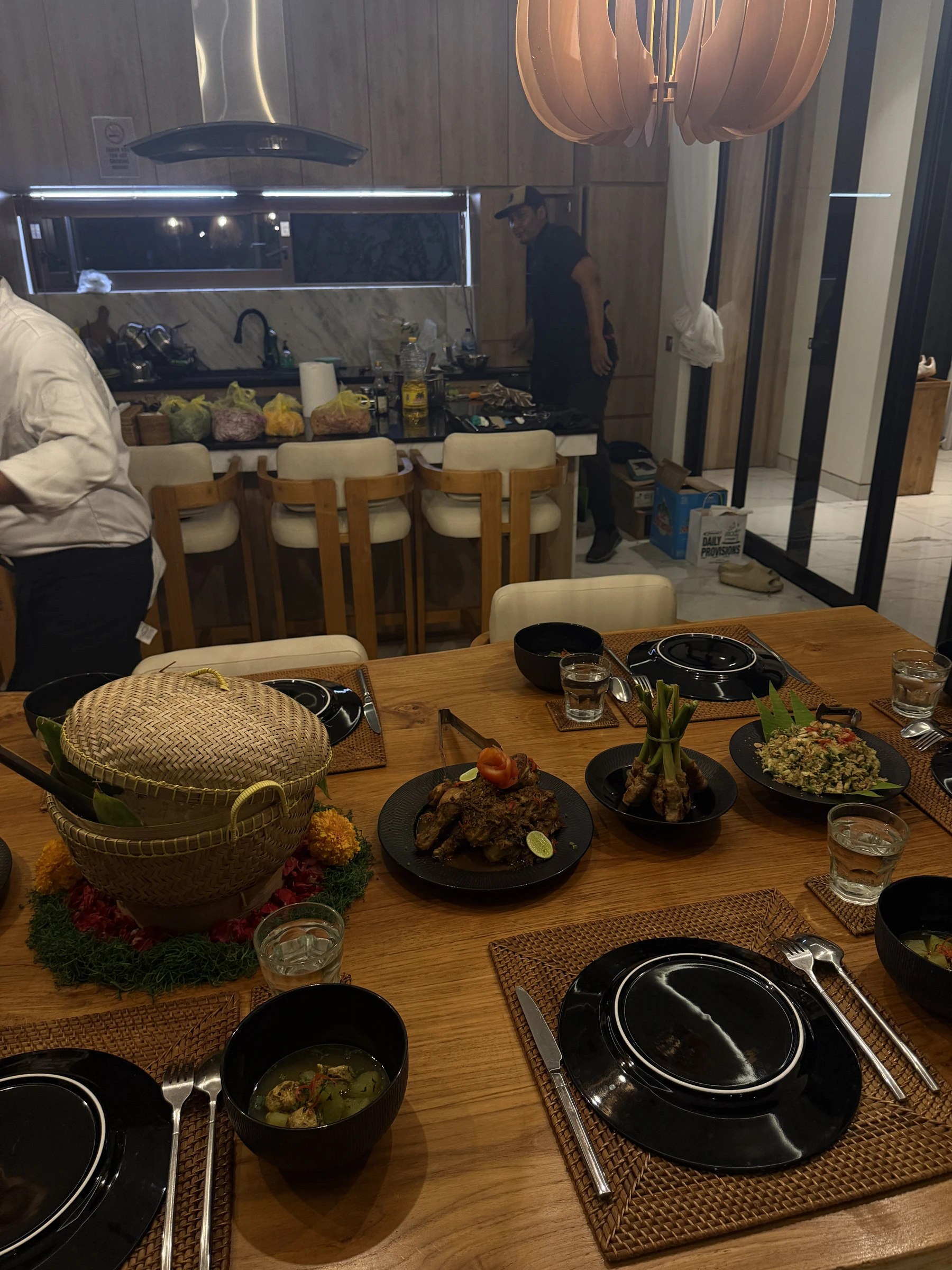 Schwarzes Geschirr, gewebte Tischsets und warmes Holz beim Dinner in der Residence auf Bali
