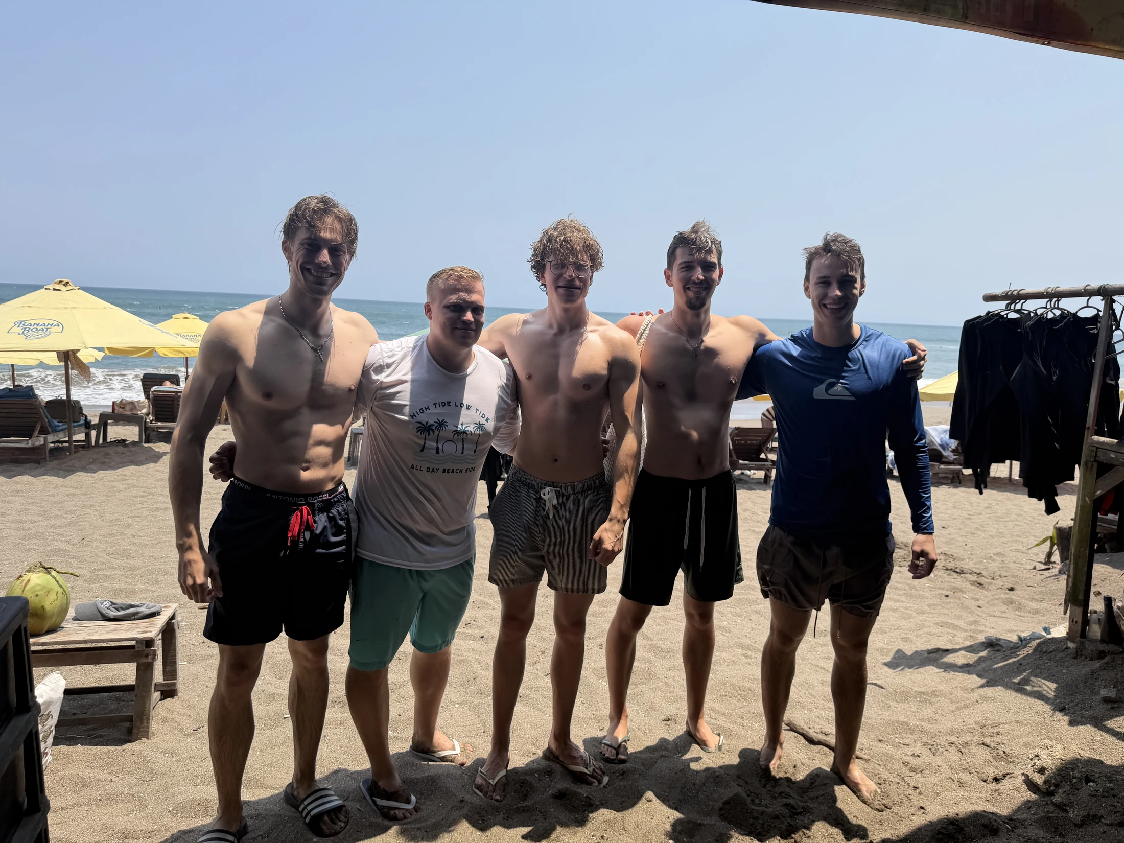 Fünf Teilnehmer stehen gemeinsam am Strand auf Bali und lächeln in die Kamera